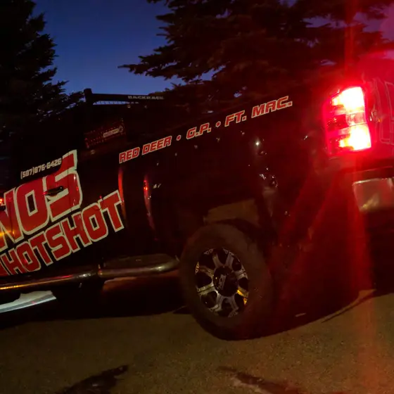 NOS Hotshot truck at dusk with the brake lights lit, RED DEER · G.P. · FT. MAC. lettered along the box